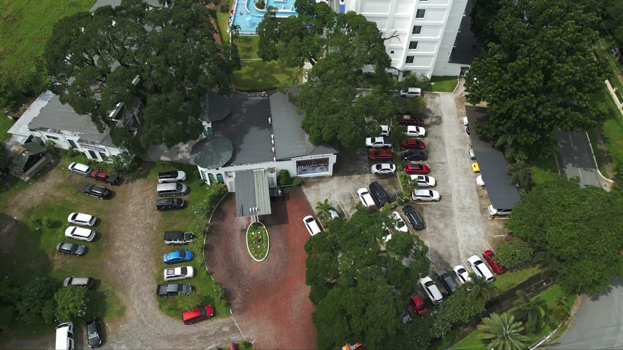 A high-angle drone shot showcases the spacious parking area of a luxury resort, seamlessly integrated into its elegant surroundings.