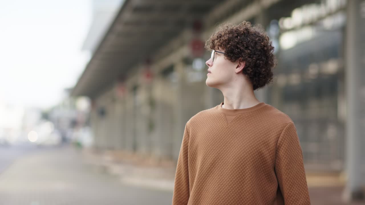 Bevægelse spottet: Mand iført briller og brun sweater scanner glaspaneler på overdækket gangbro