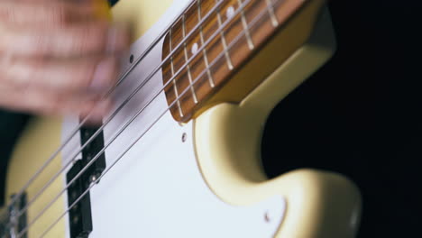 bassist plays white guitar holding yellow pick closeup