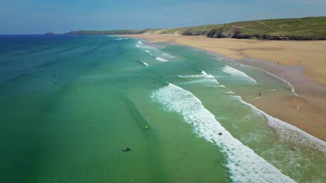 Surfistas-En-La-Playa-De-Perranporth-Con-Olas-Turquesas-A-Lo-Largo-De-La-Costa-De-Cornualles,-Reino-Unido