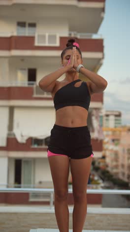 young woman practicing yoga on a rooftop