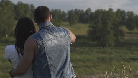 close backside view man in denim vest hugs brunette lady