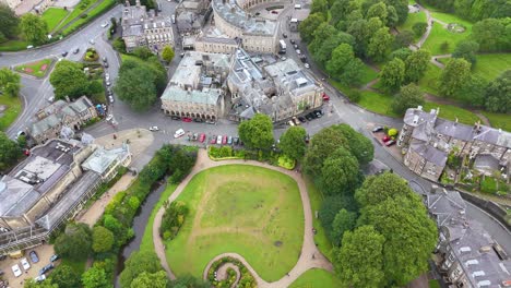 drone camera smoothly flies over a green park and historic crescent buildings in a picturesque english town, under soft daylight with steady movement