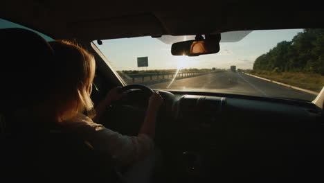 middle-aged female driver drives car in setting sun 4