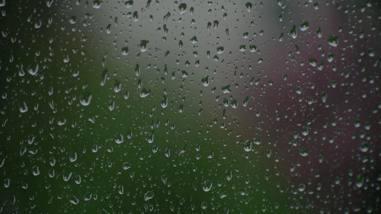 Window in focus while raindrops fall on it in the out-of-focus exterior