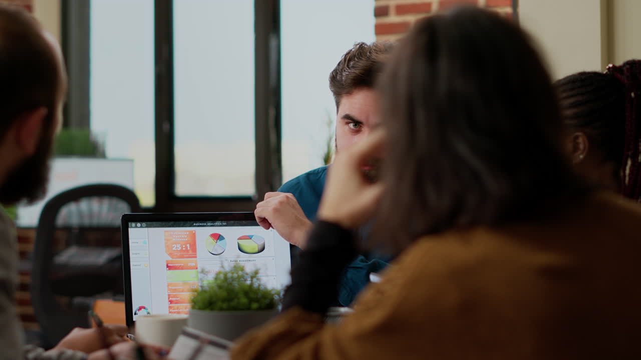 Project manager pointing at business charts on laptop