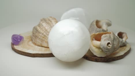 sea shells sitting on top of a wooden craft with two crystal balls and small gem stones in between - close up shot