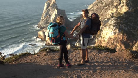 una pareja de turistas de mochila de pie en un acantilado