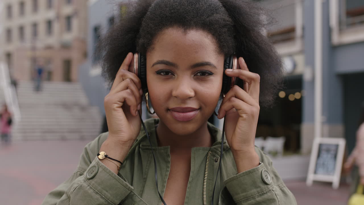 portrait au ralenti d'une jeune femme afro-américaine à la mode portant des écouteurs écoutant de la musique