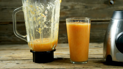 glass of a fruit juice with juicer on wooden table 4k