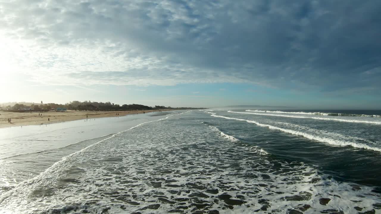 vuelo rápido a baja altitud como un jet sobre las olas entrantes en pismo beach con el amanecer reflejándose en la superficie del océano
