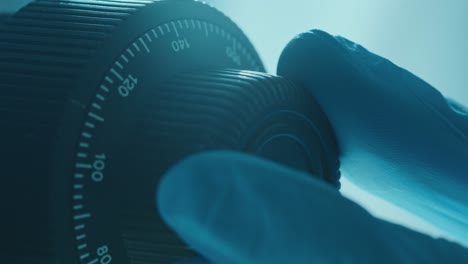 hand of laboratory worker adjusting focus knob of microscope