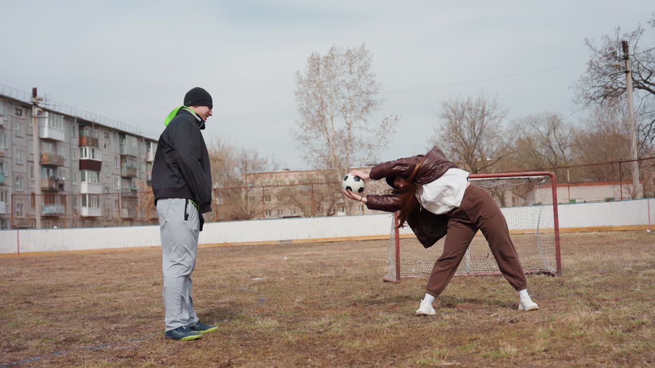Atleta practicando estiramientos con la guía de un entrenador, jugadora de fútbol haciendo calentamiento bajo la supervisión de un entrenador, joven realizando ejercicios de estiramiento con balón durante la sesión de calentamiento del equipo