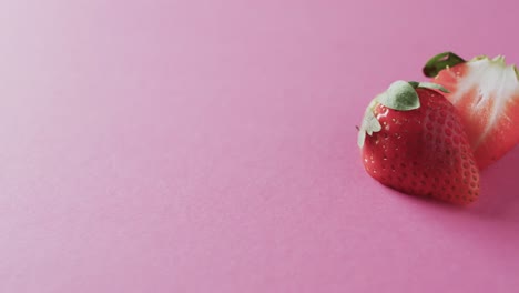 Video-of-halved-strawberry-with-copy-space-over-pink-background