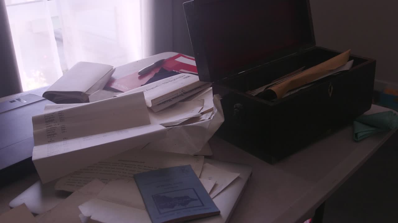 An antique box surrounded by vintage papers on a table, illuminated by gentle light. Ideal for historical documentaries or nostalgic projects