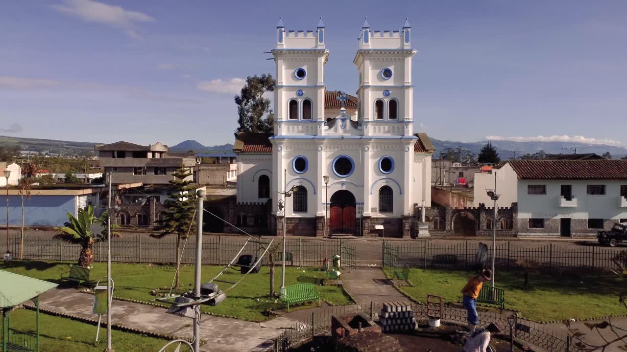 fotografía de un dron pasando cerca de algunas ramas de árboles, en 4k de la iglesia de tucuso en la ciudad de machachi, pichincha, ecuador, en un día soleado