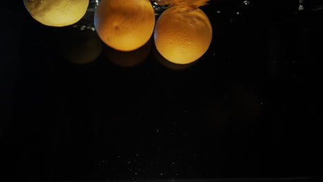 lemons and oranges splashing into water slow motion background