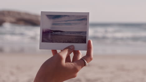 close-up-hand-holding-photograph-of-beautiful-seaside-beach-tourist-enjoying-photographing-vacation-experience