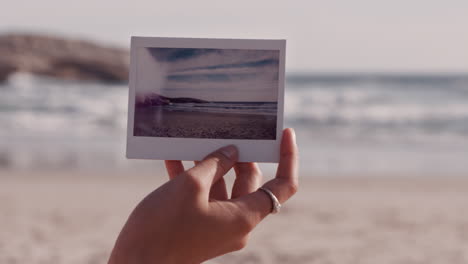 close up hand holding photograph of beautiful seaside beach tourist enjoying photographing vacation experience