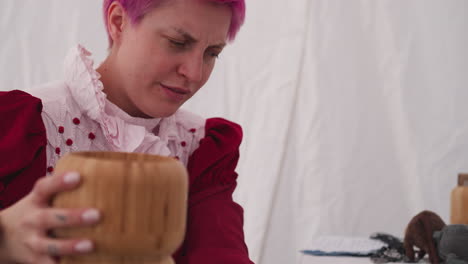 una bruja de cabello rosa vierte el ingrediente para crear una poción