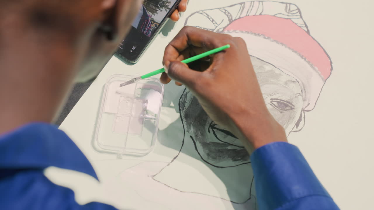 Black art student practicing portrait painting with green pencil in classroom studio, attentive hand refining facial shading on paper, smartphone reference for tonal study, focused learning mood