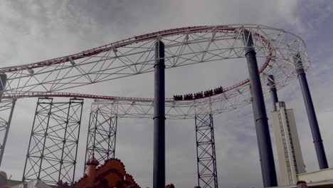 4k rollercoaster speeding around corner high above theme park in uk