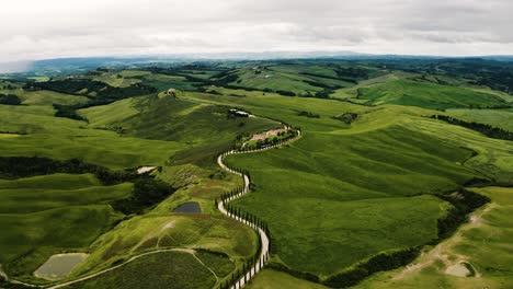 Aerial-view-of-a-winding-road-in-Italy's-countryside,-leading-to-a-farmhouse