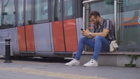 young man sitting on the steps in the street texting on the phone.