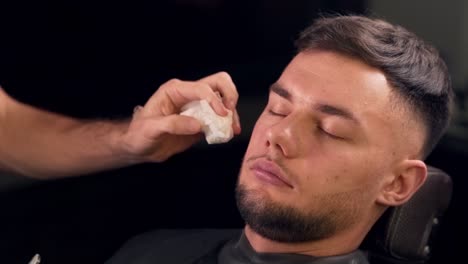 closeup of a barber shaves a young pretty guy's barber shop