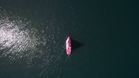 Velero-En-Un-Lago-Profundamente-Azul,-Tiro-De-Arriba-Hacia-Abajo-De-Dron