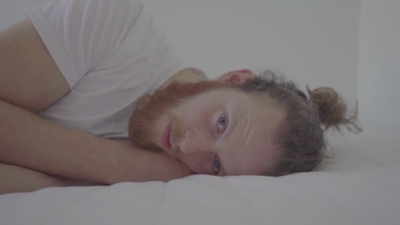 hombre triste acostado en una cama