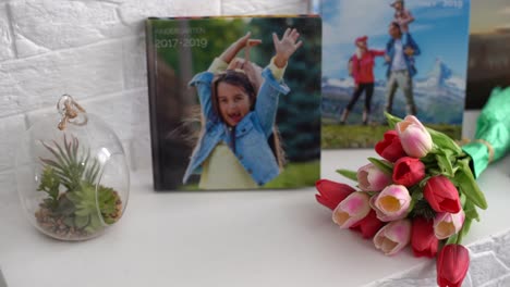 photo book and flowers tulips as a holiday gift lie on the shelf