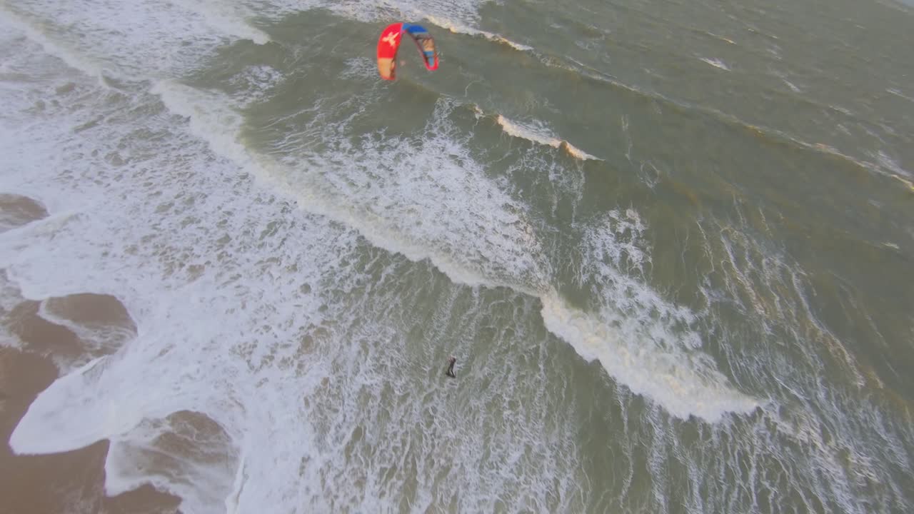 kitesurfer saltando y un dron volando por encima y alrededor de la cometa