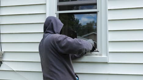 Einbrecher-öffnet-Ein-Fenster-Mit-Einem-Brecheisen-Und-Beginnt,-In-Ein-Haus-Zu-Klettern