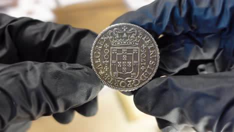 collector examining portuguese silver coin from the modern age