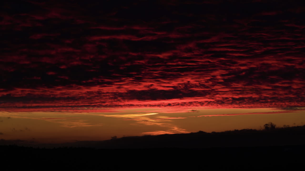 Dramatic red sunset reflecting on cloud blanket in nature, time lapse