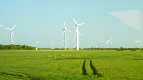 muchas turbinas eólicas en campos verdes contra el cielo azul en el norte de alemania