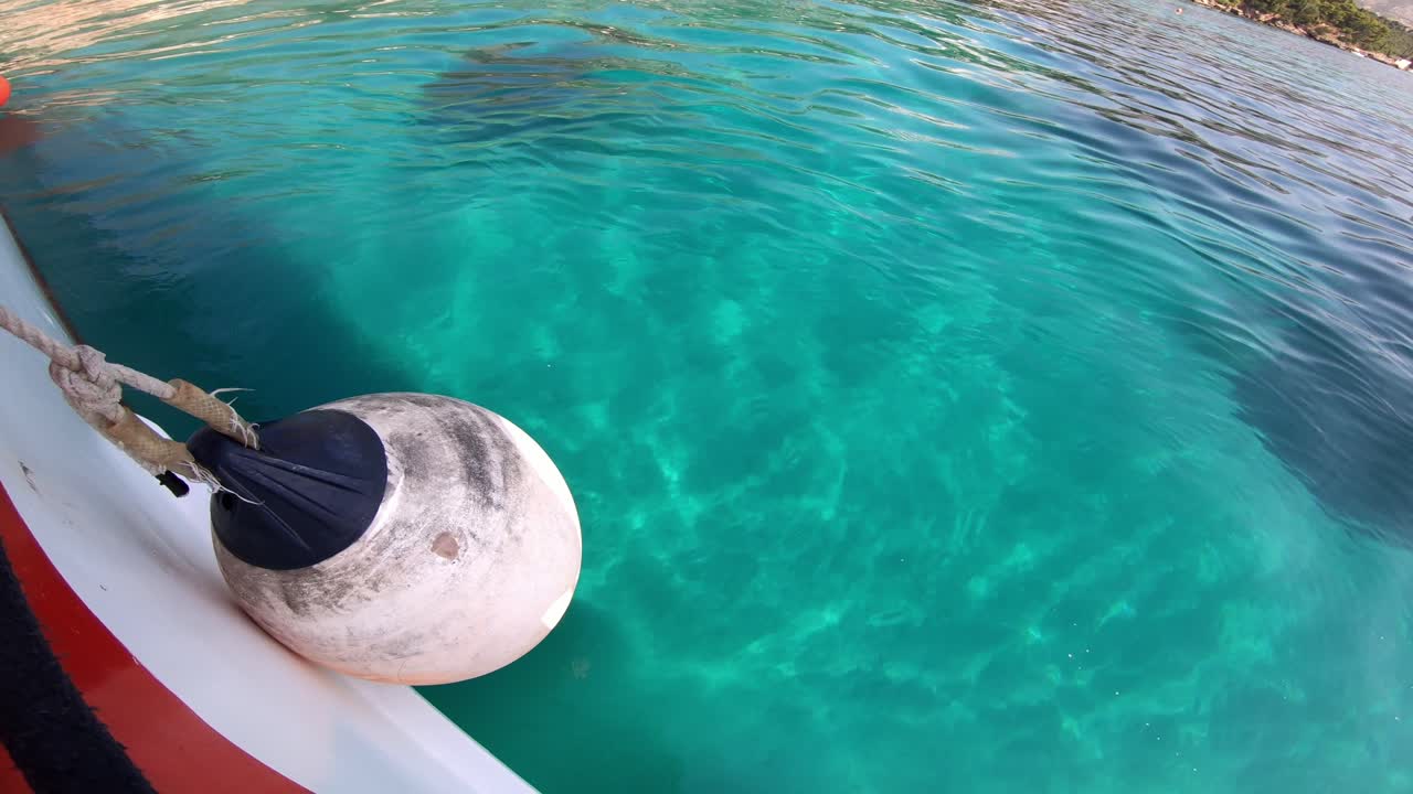Amazingly clear turquoise waters looking overboard of a white red boat