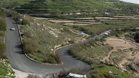 white racing car drifting on the curved road track uphill - aerial shot