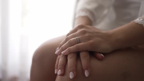 close up of bride’s hands resting gently, showing engagement ring in soft light