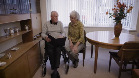elderly couple reading a book together at home