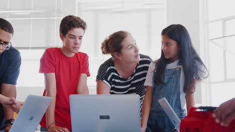 students with teachers in after school computer coding class learning to program robot vehicle