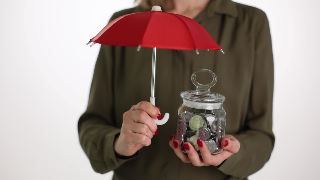Donna che tiene un ombrello sopra un barattolo di monete a simboleggiare la protezione finanziaria