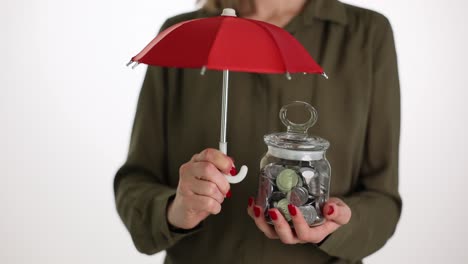woman holding umbrella over jar of coins symbolizing financial protection