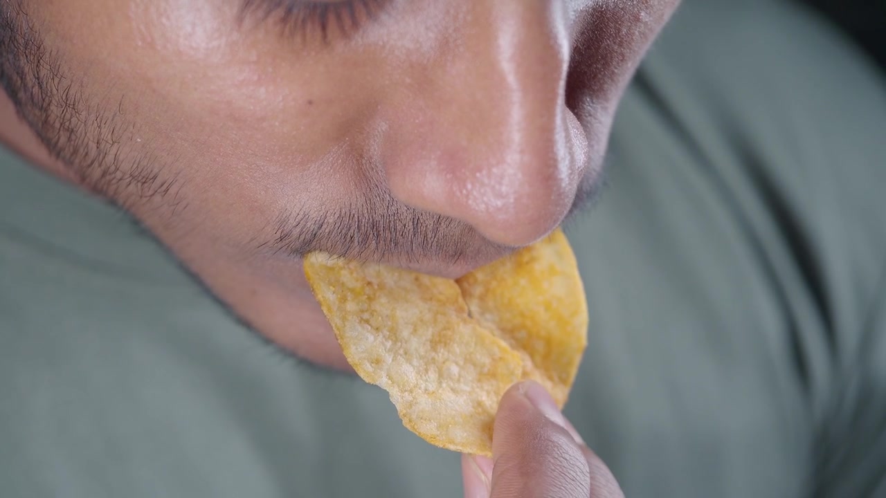 Young Man Eating a Crispy Potato Chip