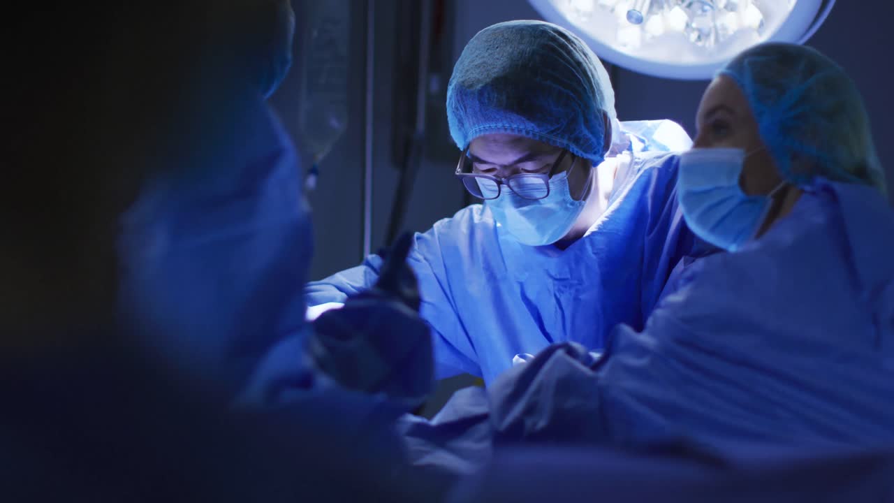 Různí chirurgové s rouškami a ochranným oděvem na operačním sále