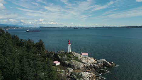 aerial view tilting down point atkinson lighthouse in lighthouse park near vancouver city on an sunny day with some clouds in british columbia, canada