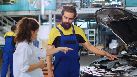mecánico mostrando daños en el coche de una mujer