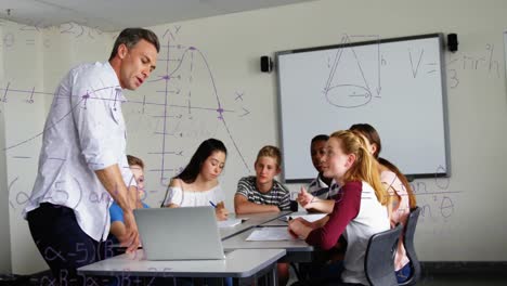 ecuaciones matemáticas flotando contra un profesor masculino usando una computadora portátil para enseñar a los estudiantes