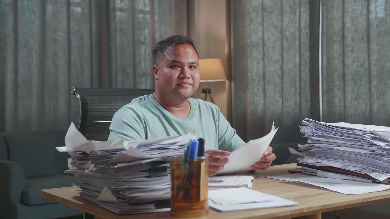Fat Asian Man Crossing Arms And Smiling To Camera While Working With Documents At The Office